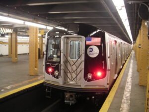 new york city subway train pulling up to the platform of a station underground