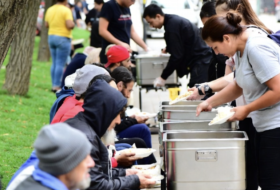 homeless people being served food in a park during the day time