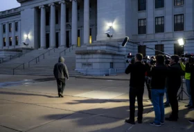 man walking outside courthouse with press filming him