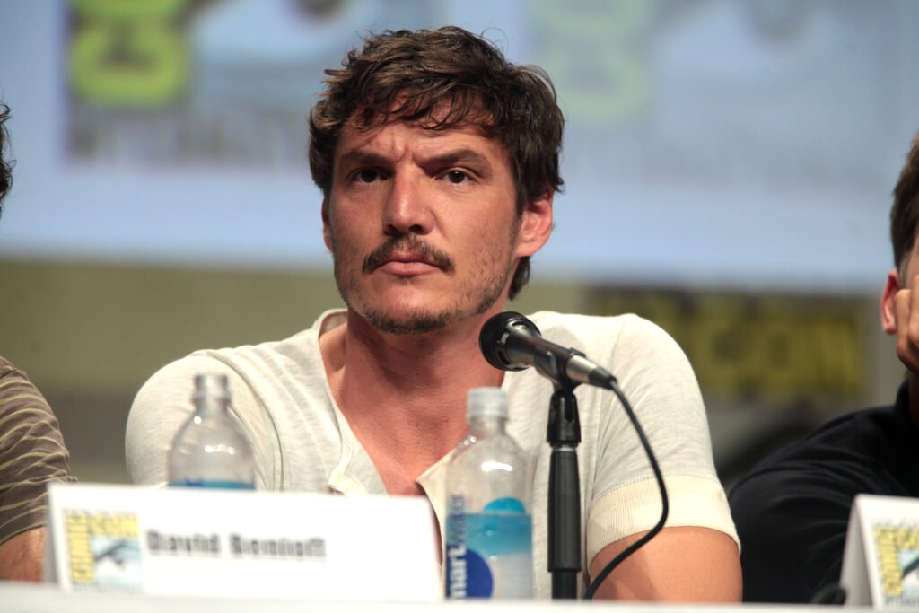 Pedro Pascal speaking at a panel while seated, photo credit: wikimedia commons