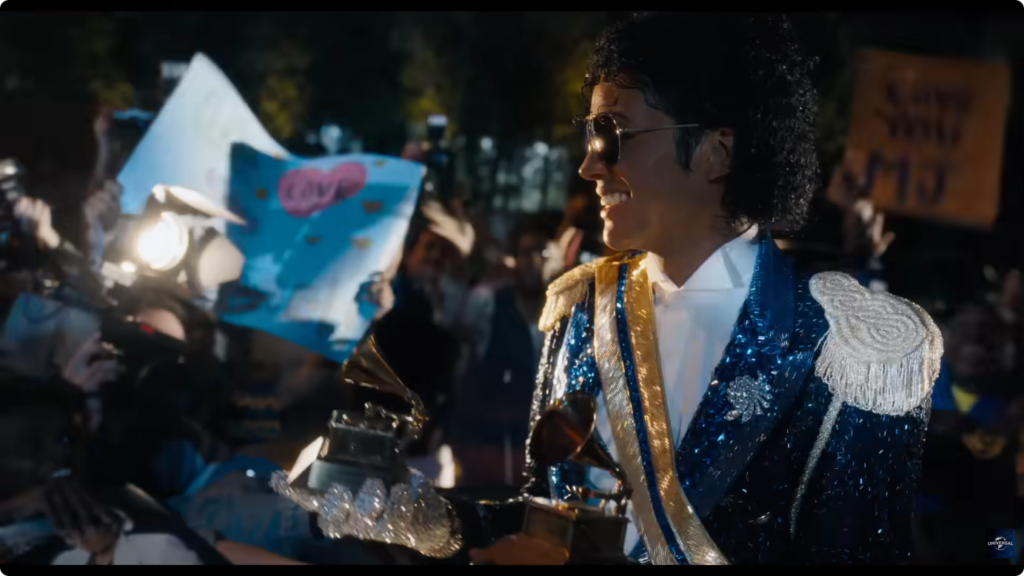 Still from the film "Michael" of Michael Jackson holding a grammy with paparazzi