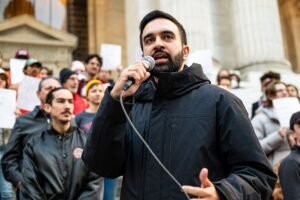 Zohran Mamdani speaking outside at an event