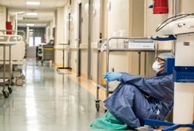 masked healthcare worker sitting on the ground inside hospital
